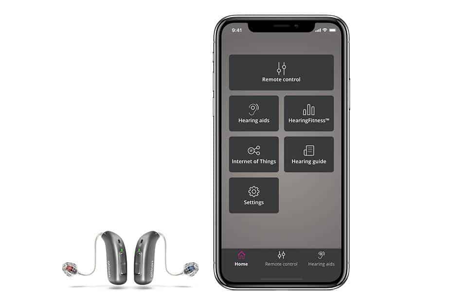 A pair of Oticon hearing aids next to a smartphone running the Oticon ON app